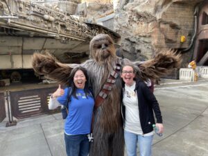 Leslie with her thumb up and Elisabeth smiling like a fool with Chewbacca, hands raised in joy, during their visit to Galaxy's Edge, the Star Wars related area of Disneyland Park in Anaheim, CA.